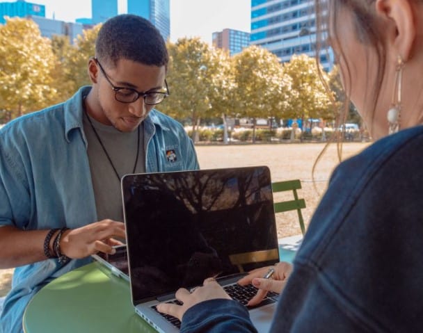 Two friends on their laptops sharing their $20 refer-a-friend codes.